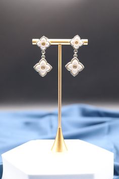 Dangling Pearl Gold Clover Earrings feature delicate clover-shaped pendants adorned with lustrous pearls that gently sway with your movements, adding a touch of elegance and charm to your attire. These earrings are a symbol of luck and sophistication, making them a graceful choice for special occasions or everyday wear. Length: 1.73” Width: 0.79” Closure: Pushed Back Material: Brass with 18K Gold Plating with Rhodium Coating Lead Free and Hypoallergenic Elegant Pearl Earrings With Flower Charm, Elegant White Flower Earrings With Pearl Charm, Elegant Metal Jewelry With Flower Charm, Elegant Dangle Pearl Earrings With Flower Charm, Elegant Metal Earrings With Flower Charm, Elegant Silver Pearl Flower Earrings, Elegant Metal Flower Charm Earrings, Elegant Hypoallergenic Silver Flower Earrings, Silver Pearl Drop Earrings In Flower Shape