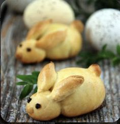 small buns shaped like animals sitting on top of a wooden table next to eggs