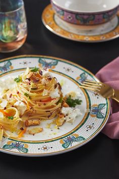 a plate topped with pasta and vegetables on top of a table next to two glasses