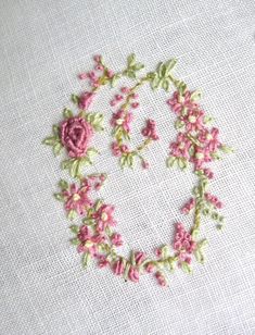 an embroidered letter o with pink flowers on it