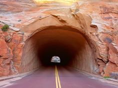 a car is driving through a tunnel on the side of a road with yellow lines