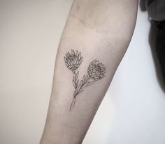 a black and white photo of a flower tattoo on the left arm, with three flowers in it