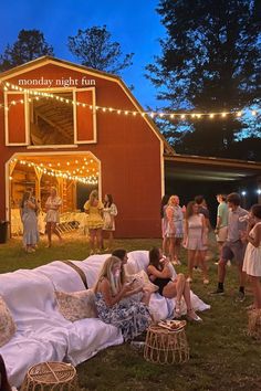 a group of people sitting on top of a grass covered field next to a barn