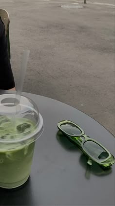 a green drink sitting on top of a table next to a pair of glasses