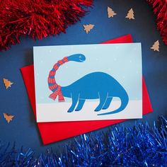 a card with an image of a blue dinosaur wearing a red and white striped scarf