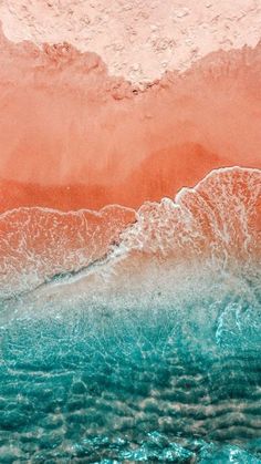 an aerial view of the ocean with orange and blue waves coming in from the water