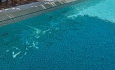 an empty swimming pool with chairs and umbrellas