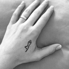 a woman's hand with a small bow tattoo on her left wrist and an arrow in the middle