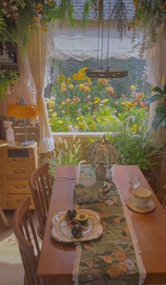 a dining room table set for two with flowers in the window and potted plants