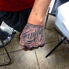 a man with a tattoo on his hand is holding the word family in front of him