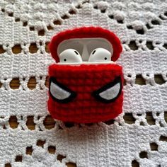 an earphone case made to look like a deadpool character is sitting on top of a crocheted doily