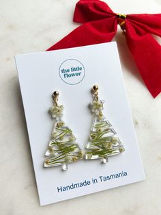 the little flower handmade christmas tree earrings are on display in front of a card