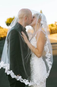 a bride and groom kissing under a veil