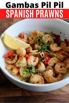 a white bowl filled with shrimp and garnish next to a slice of lemon