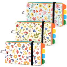 three notebooks with floral designs on them, each lined up in different colors and sizes