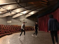 two men are dancing in an empty auditorium