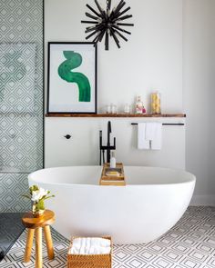 a white bath tub sitting in a bathroom next to a wall mounted art piece on the wall