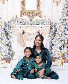 a woman and two children sitting in front of a christmas tree wearing matching green pajamas