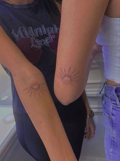 two girls with matching tattoos on their arms