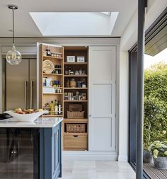 a kitchen with an open pantry and skylight above the countertop, in front of a large window