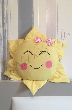 a yellow pillow with a pink bow on it's head is hanging from the wall