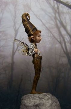 a fairy standing on top of a rock in the woods