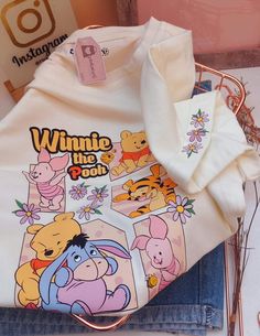 winnie the pooh t - shirt sitting on top of a pair of blue jeans