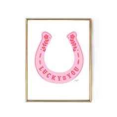 a pink horse shoe with the words lucky you on it is mounted in a gold frame