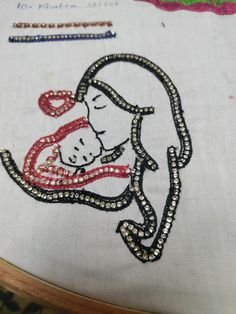 a close up of a embroidery on a piece of cloth with an image of a woman holding a baby