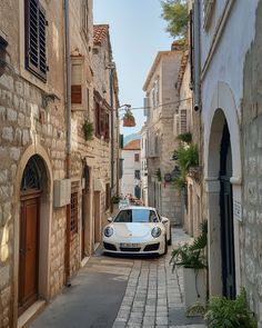 a white sports car parked on the side of an alleyway between two stone buildings