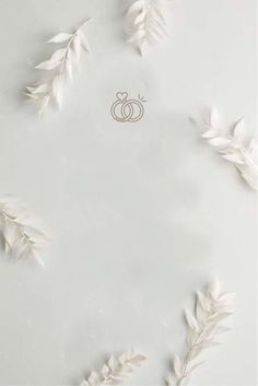 the wedding ring is surrounded by white feathers and leaves, as well as an arrow