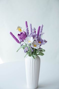 a white vase filled with purple and white flowers