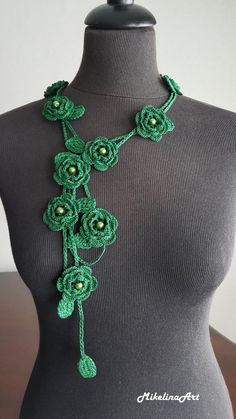 a green crocheted flower necklace on a mannequin headpiece with beads