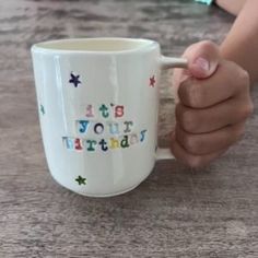 a person holding a coffee mug with the words it's your birthday on it