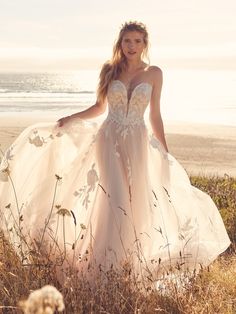 a woman in a wedding dress standing on the beach