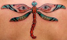 a woman's back with an artistic tattoo design on her chest and eyes behind the dragonfly