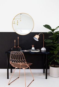 a desk with a mirror, chair and potted plant