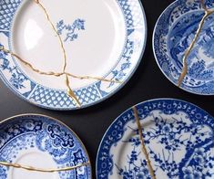 four blue and white plates with twig stems sticking out of the top, on a black surface