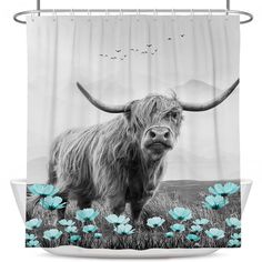 a black and white photo of a long haired cow with blue flowers in front of it