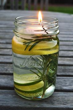 a jar filled with liquid sitting on top of a wooden table next to a lit candle