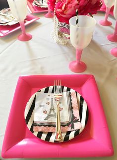 the table is set with pink plates and silverware