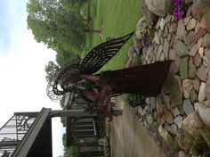 a metal angel sculpture sitting on top of a rock garden bed