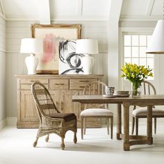 a dining room table and chairs in front of a painting