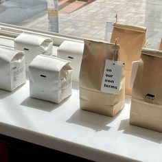 several bags are sitting on a window sill in front of the windowsill, one has a sign that says on our own towns