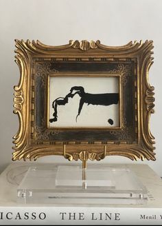 a gold frame with a black and white painting on it