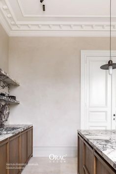 an elegant kitchen with marble counter tops and wooden cabinetry, along with white walls