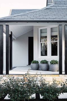 a white house with black shutters and two planters on the front porch area