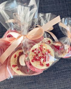 a hand holding some cookies wrapped in cellophane with ribbons and bows on them