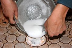 someone is mixing something in a bowl on the floor with their hands and feet behind them