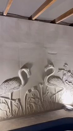 two flamingos are standing next to each other on a wall